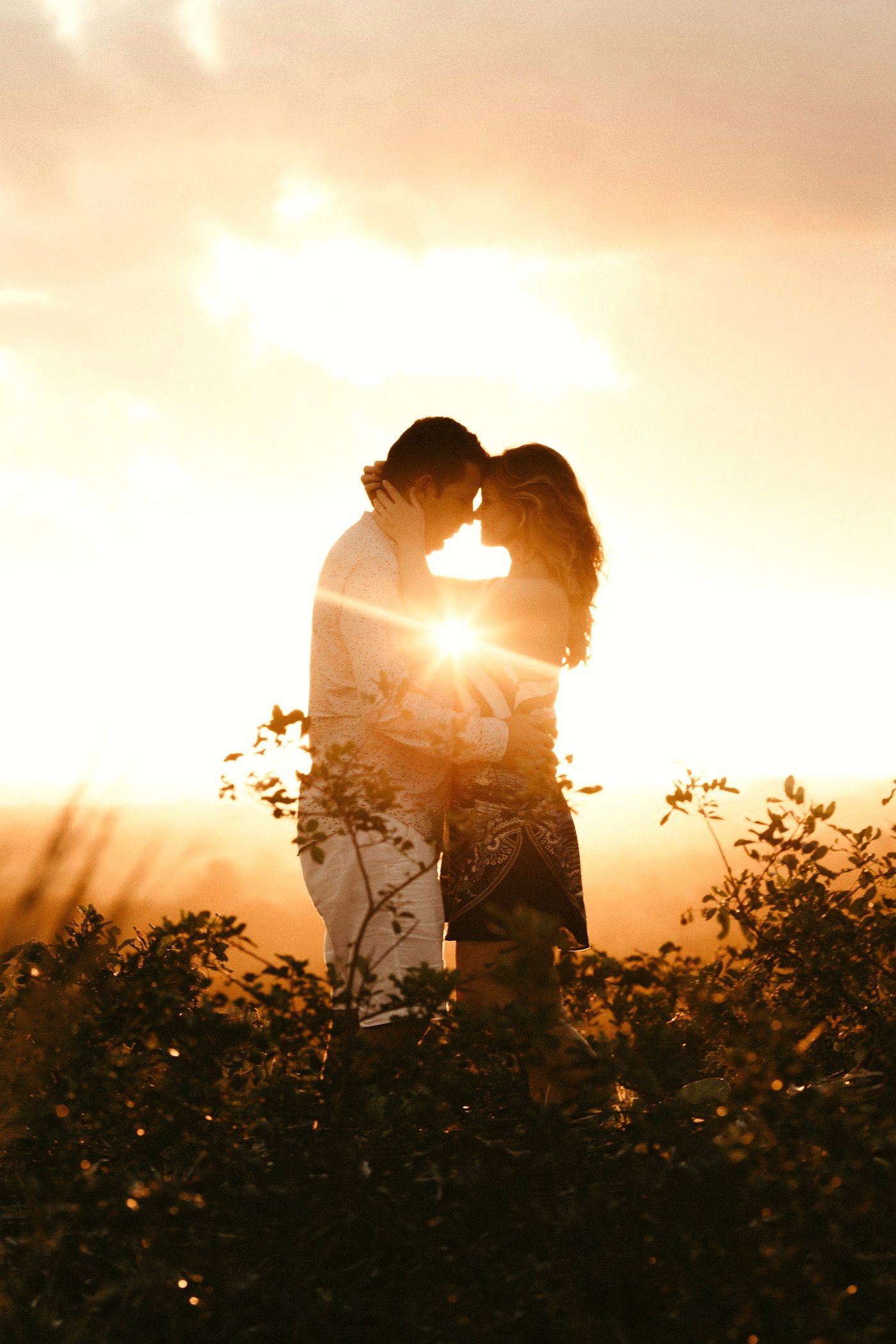 A couple laughing together during a warm golden-hour engagement session