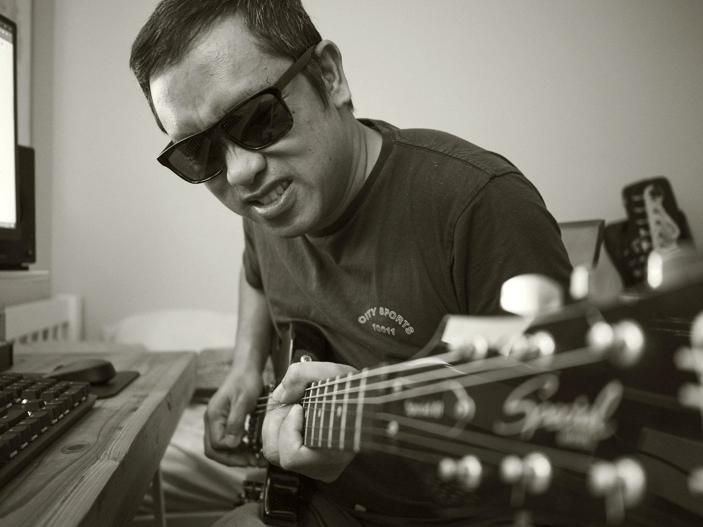 A musician mid-performance with a guitar, shot in moody black and white